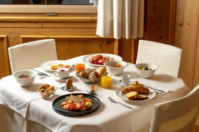 a table with breakfast foods on a white table cloth at Hotel Gran Paradis in Campitello di Fassa