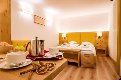 a hotel room with a bed and a table with food at Hotel Gran Paradis in Campitello di Fassa