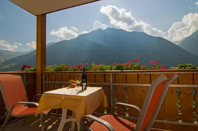 a table and chairs on a balcony with a view of mountains at Gasthaus Jaufenblick in San Martino