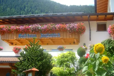 a building with lots of flowers on a balcony at Gasthaus Jaufenblick in San Martino