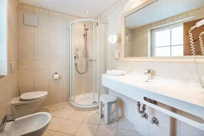 a bathroom with a sink and a shower and a toilet at Hotel Scherlin in Ortisei