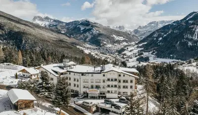a hotel in the mountains with snow on the ground at Hotel Scherlin in Ortisei