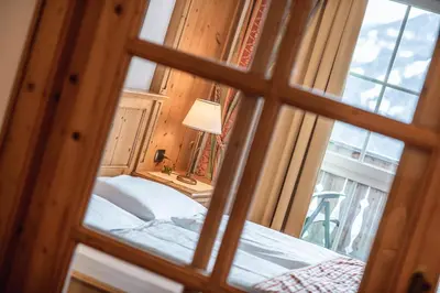 a room with a window with a bed and a lamp at Hotel Scherlin in Ortisei