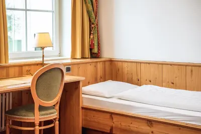 a bedroom with a bed and a desk and a chair at Hotel Scherlin in Ortisei