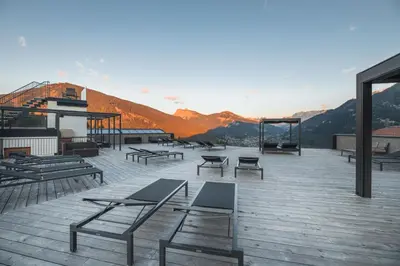 a deck with benches and tables on top of a mountain at Hotel Scherlin in Ortisei