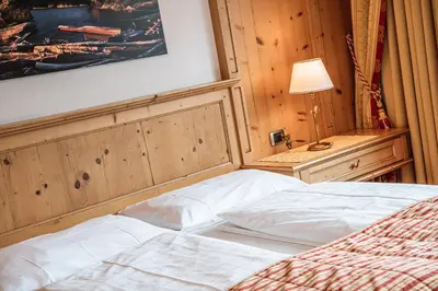 a bedroom with a bed and a lamp on a table at Hotel Scherlin in Ortisei