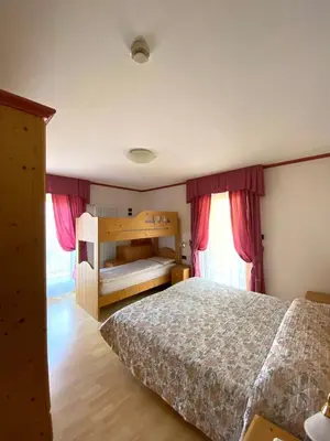 a bedroom with a bed and two bunk beds at Hotel Chalet Alaska in Pozza di Fassa