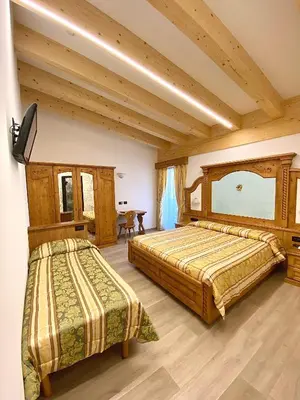 two beds in a room with wooden ceilings at Hotel Chalet Alaska in Pozza di Fassa