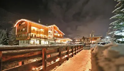 a building at night with snow on the ground at Hotel Chalet Alaska in Pozza di Fassa