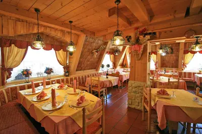 a restaurant with tables and chairs in a room at Hotel Chalet Alaska in Pozza di Fassa