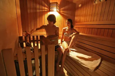 a boy and a girl sitting in a sauna at Hotel Chalet Alaska in Pozza di Fassa