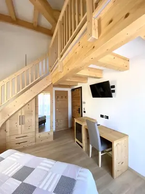 a bedroom with a bed and a desk with a tv at Hotel Chalet Alaska in Pozza di Fassa