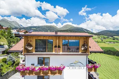 a house with a balcony with flowers on it at Pension Sonnenhof in Maranza