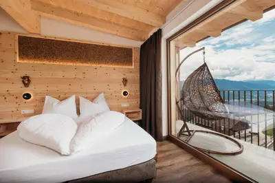 a bedroom with a bed and a balcony with a hammock at Pension Sonnenhof in Maranza
