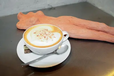 a cup of coffee sitting on a table with a cookie at Pension Martha in Postal