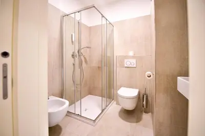 a bathroom with a shower and a toilet and a sink at Pension Martha in Postal
