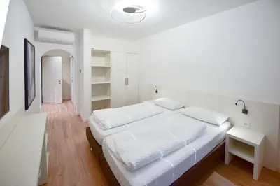 a white bedroom with a large bed and a desk at Pension Martha in Postal