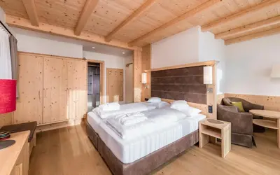 a large bedroom with a large bed and a desk at Hotel Villa Kastelruth in Castelrotto