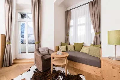 a living room with a couch and a chair and a window at Hotel Villa Kastelruth in Castelrotto