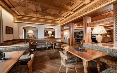 a restaurant with wooden ceilings and tables and chairs at Hotel Villa Kastelruth in Castelrotto