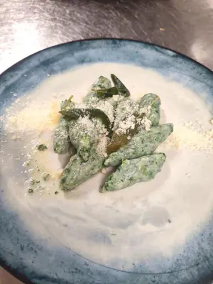 a plate of food with broccoli in a dip at Albergo Bucaneve in Malosco