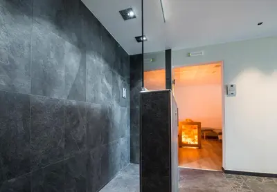 a bathroom with a black tiled wall at Albergo Bucaneve in Malosco