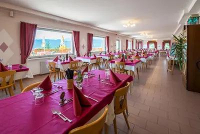 a dining room with tables and chairs with red napkins at Albergo Bucaneve in Malosco