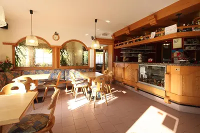 a kitchen with wooden cabinets and tables and chairs at Albergo Bucaneve in Malosco