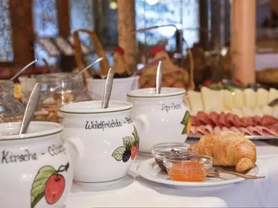 a table with three cups of jam and a plate of food at Hotel Pension Sonnegg in Saltusio