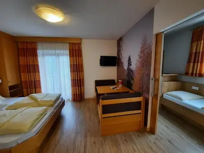 a room with two beds and a table in it at Hotel Pension Sonnegg in Saltusio