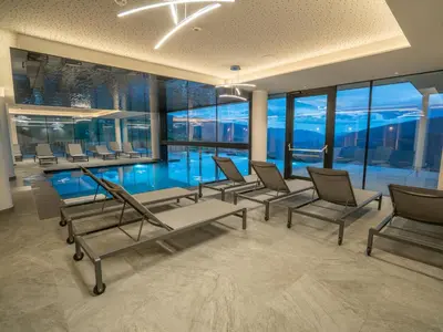 a pool room with chairs and a swimming pool at Hotel Purvita - Ski In Ski Out - Infinity Pool in Maranza