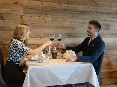 a man and woman sitting at a table with wine glasses at Hotel Purvita - Ski In Ski Out - Infinity Pool in Maranza