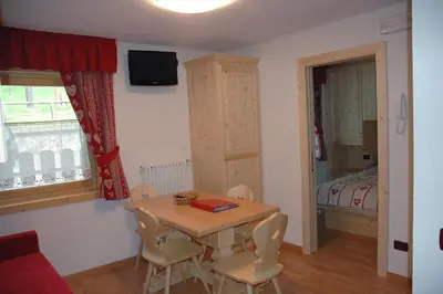 a small room with a table and chairs and a bed at Appartamenti Albert in Canazei