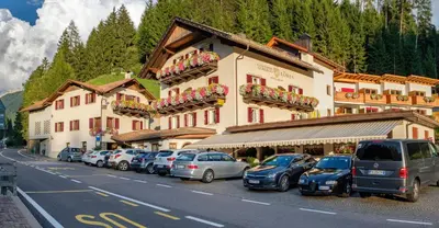 a large building with cars parked in a parking lot at Gasthof Löwen in Nova Levante