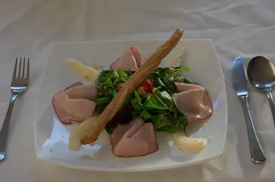 a plate of food with meat and salad on a table at Gasthof Löwen in Nova Levante