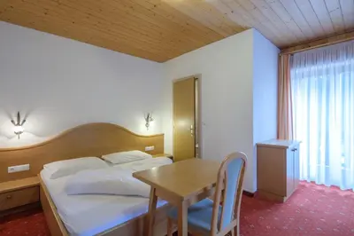 a bedroom with a bed and a table and a window at Gasthof Löwen in Nova Levante