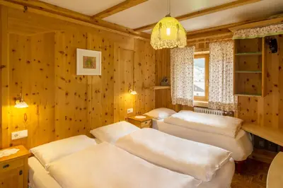 a bedroom with three beds and a chandelier at Villa Insam in Selva di Val Gardena