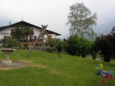 a wooden frame in the grass in front of a house at Garni Schneeburghof in Tirolo