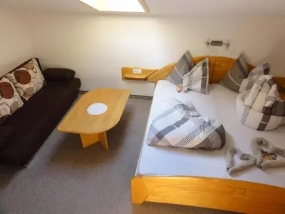 a room with a bed and a couch and a table at Garni Schneeburghof in Tirolo