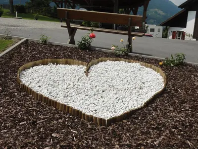 a heart shaped rock on the ground next to a bench at Garni Schneeburghof in Tirolo