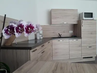 a kitchen with wooden cabinets and purple flowers on a counter at Appartment Charly in Siusi
