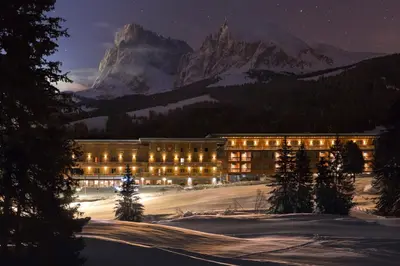 a building with lights in front of a mountain at Sporthotel Floralpina in Alpe di Siusi