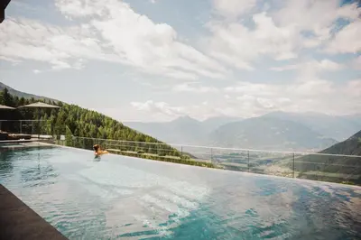 a person in a infinity pool with a view of mountains at Mountain Lodge Prennanger in Schenna