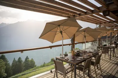 a table with chairs and umbrellas on a deck at Mountain Lodge Prennanger in Schenna
