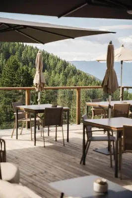 a patio with tables and umbrellas on a deck at Mountain Lodge Prennanger in Schenna