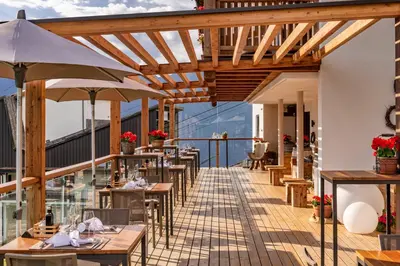a restaurant with tables and umbrellas on a balcony at Mountain Lodge Prennanger in Schenna