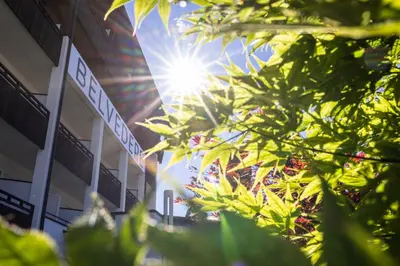 a building with the sun shining through the trees at Hotel Belvedere - Adults Only - 14 plus in Naturno