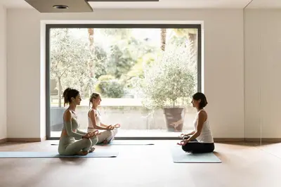 four women sitting in a yoga pose in front of a window at Lake Spa Hotel SEELEITEN in Caldaro