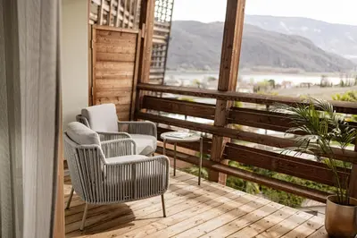 two chairs and a table on a balcony with a view at Lake Spa Hotel SEELEITEN in Caldaro