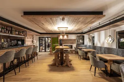 a restaurant with wooden floors and tables and chairs at Alpstyle Hotel Albolina Wellness & Beauty in Canazei